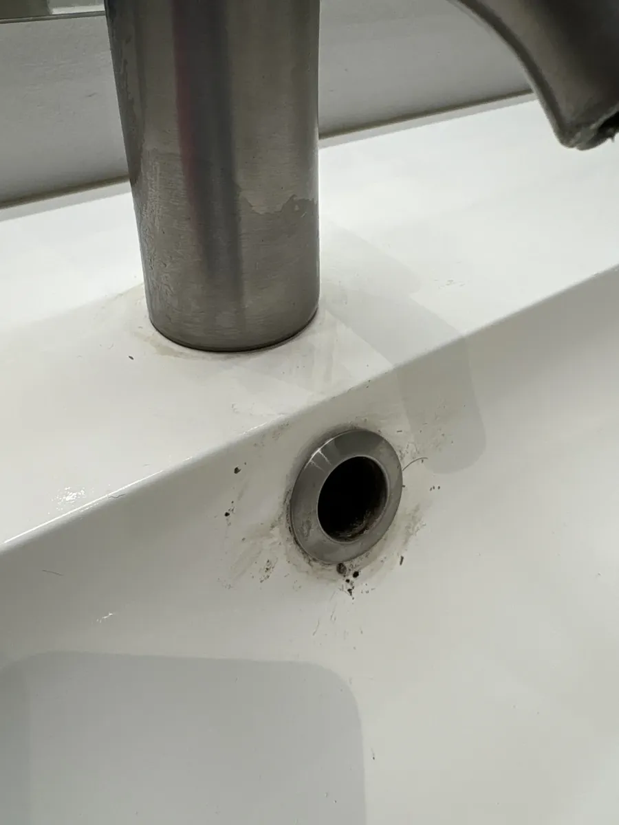 Håndvask med kalk og snavs omkring afløbet, før rengøring